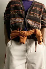 Cárdigan marrón de punto jacquard con mezcla de algodón y lino, con cuello en V, cierre frontal de botones y bolsillos en la cadera. Presenta un diseño estampado de franjas horizontales con patrones geométricos en tonos naranjas, blancos y lilas.