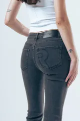 Jean de corte bootcut y tiro medio, color gris oscuro desgastado. Presenta un diseño de pierna recta que se ensancha ligeramente hacia el ruedo, con cierre frontal y bolsillos clásicos.