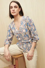 Blusa celeste con estampado floral en tonos beige y marrón, escote en V, mangas 3/4 abullonadas y frunce en la cintura.