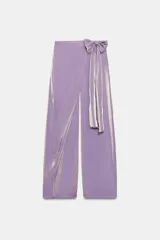 Pantalón de tiro alto con diseño cruzado tipo pareo, pernera ancha y detalle de lazada lateral. Presenta un acabado con efecto brillante.
