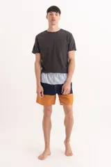 Short de baño con diseño de bloques de color horizontal en tonos celeste, azul marino y mostaza, con cintura elástica y cordón ajustable.