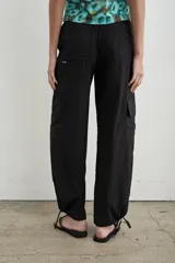 Pantalón estilo cargo color negro, confeccionado en tela avión, con cintura elastizada ajustable mediante cordón y puños regulables en los tobillos con tiras para ajustar.