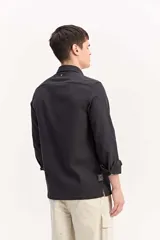 Camisa de manga larga color beige, de tejido texturado con cierre frontal de botones y cuello camisero clásico.
