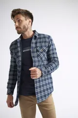 Sobrecamisa de viyela para hombre con estampado de cuadros en rojo y negro. Presenta cierre frontal con botones, bolsillos en el pecho con solapa y botón, y un interior capitoneado para mayor abrigo. Cuenta con un logo en grifa de cuero.