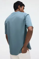 Remera de manga corta color verde, confeccionada en punto liviano, con cuello redondo ribeteado, hombros caídos, bajo recto y corte relajado.