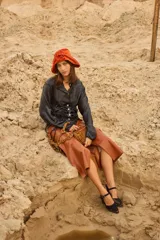 Camisa de satén color negro con acabado brillante, cuello en V, cierre frontal con botones de nácar y diseño ajustable con cordones laterales para fruncir.