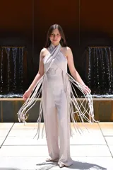 Mono largo color celeste, con escote halter cruzado, corte ajustado en la cintura y detalle de flecos largos en los laterales.