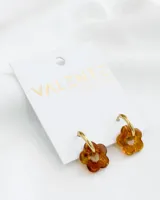 Aros colgantes con aro dorado de acero y dije de acrílico color caramelo con forma de flor.