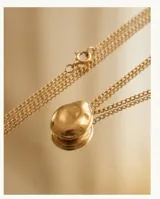 Collar de acero con baño de oro, compuesto por una cadena fina y un dije circular de diseño orgánico y superficie lisa.