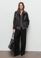 Pantalón de vestir negro de tiro medio con diseño wide leg, detalle de pinzas frontales, bolsillos laterales y cierre delantero con botón, gancho y cremallera ocultos.