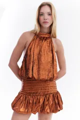 Top metalizado color cobre, con cuello halter y diseño balloon con caída fluida.