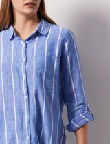 Camisa de lino marca Dash, color beige con rayas verticales blancas, cuello con solapa, cierre frontal de botones, bolsillo aplicado en el pecho y mangas largas con sistema para arremangar mediante presilla y botón.