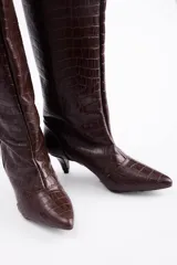 Bota de caña alta confeccionada en cuero vacuno con textura de reptil. Presenta un diseño de punta fina y un tacón bajo tipo kitten heel.
