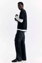 Pantalón cargo negro de nylon, de corte regular con cintura elástica ajustable con cordón. Cuenta con bolsillos laterales con cierre, bolsillos cargo con solapa en las piernas, bolsillos traseros con cierre y tensores en los tobillos.