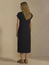 Vestido midi de color negro, con cuello redondo, mangas cortas y tajo lateral en el ruedo. Confeccionado en tejido fluido y suave.
