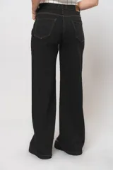 Pantalón jean negro de corte wide leg con costuras en tono beige y tela alicrada.