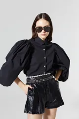 Short negro de tiro alto con efecto metalizado y textura tipo brocato, cintura con pliegues y bolsillos laterales.