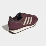 Championes Adidas modelo SL 72 RS, de diseño retro en color bordó con detalles en beige. Confeccionados con base de cuero y superposiciones de gamuza, presentan las icónicas tres rayas laterales, mediasuela de EVA y suela de caucho.