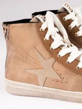 Zapatillas de caña alta color beige con detalles en marrón y animal print de leopardo en el tobillo. Presentan una estrella en el lateral y cordones blancos.