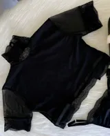Top de cuello alto confeccionado en lycra, con mangas cortas de microtul y detalles de encaje elastizado en cuello, mangas y ruedo. Presenta espalda descubierta.