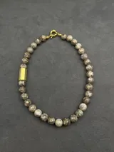 Collar de piedras naturales en tonos tierra, con detalle de tubo dorado en un lateral y cierre marinero dorado.