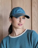 Gorra tipo visera confeccionada en cuero con textura de pelo, diseño clásico con ojales metálicos de ventilación y ajuste posterior.