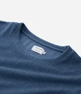 Remera de manga corta y cuello redondo, confeccionada en tejido de media malla con textura vertical. Presenta un diseño minimalista y ligero, ideal para un uso versátil y cómodo.