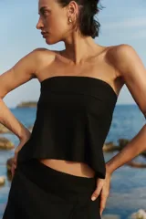 Top strapless negro con recorte en el escote, confeccionado en una mezcla de lino y rayón. Presenta un diseño con elástico y lazo para atar en la espalda.