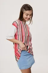 Remera oversize de manga corta con diseño de rayas verticales en tonos rojos, negros, blancos y tostados, y mangas blancas lisas.