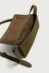 Bolso tipo bandolera de piel con acabado serraje, compartimento principal con cierre de solapa e imán, bolsillo posterior y asa de hombro ajustable.