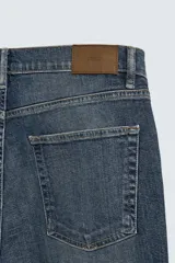 Pantalón de jean corte slim fit, color gris con efecto lavado. Presenta diseño de cinco bolsillos, cierre frontal con cremallera y botón, y tejido elástico.