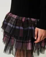 Vestido corto negro de punto liso con cuello en V y manga larga. Presenta capas de tul aplicado con estampado de cuadros multicolor.