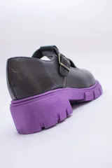 Guillermina de cuero negra con suela tractorada roja y hebilla dorada.