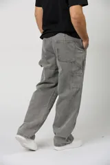 Jean baggy de hombre color gris, con diseño holgado, estilo cargo y parches en las rodillas.
