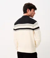 Suéter de punto Marfinno, color blanco y negro con diseño de rayas horizontales bicolor. Cuenta con cuello polo, cierre frontal completo y bolsillos laterales.