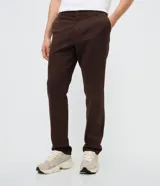 Pantalón slim de sarga lavada color marrón, con cierre de botón y cremallera, trabillas para cinturón y bolsillos laterales y traseros.