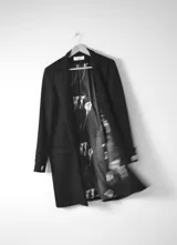 Tapado negro de lana y cashmere, de corte recto y largo a la rodilla, sin botones frontales. Tiene puños cruzados con botones dorados.