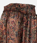 Blusa bata de chiffon con estampado paisley en tonos rojos, verdes y dorados sobre fondo negro. Presenta escote hombro a hombro con elástico fruncido y mangas largas con puños ajustados.