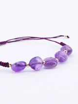Pulsera ajustable de hilo color violeta con piedras naturales de amatista en forma irregular y pequeñas cuentas doradas intercaladas.