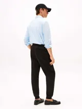 Pantalón de jogging negro de corte regular y pierna cónica, confeccionado en mezcla de algodón y poliéster. Presenta cintura con cordón, bolsillos laterales y trasero, y logo de Tommy Hilfiger bordado en la cadera.