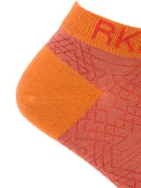 Medias cortas de fibra de bambú con diseño geométrico en tonos rojizos y detalles en naranja. Presentan el logo de la marca en el puño y en la puntera.