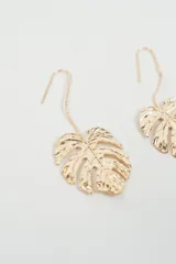 Aros colgantes con diseño de hoja tipo monstera, con acabado metálico dorado y gancho de sujeción.