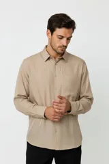 Camisa de corte holgado, color blanco, con cuello clásico, cierre frontal de botones y bolsillo en el pecho.