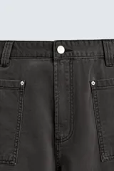 Pantalón de corte relaxed fit confeccionado en algodón, color gris oscuro. Presenta bolsillos delanteros, bolsillos laterales tipo cargo en las perneras y cierre frontal con cremallera y botón.