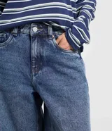 Bermuda jorts de jeans azul, corte ancho y largo por debajo de la rodilla, tiro medio con trabillas para cinturón y bolsillos traseros.