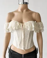 Corset blanco estilo off-shoulder, con escote en V pronunciado, volados de encaje en los hombros y cierre frontal con cordones ajustables.