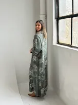 Vestido largo color verde militar con estampado floral, cuello drapeado y mangas largas de corte holgado.