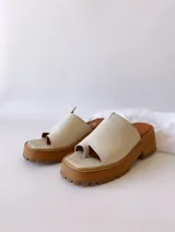 Sandalias de cuero crudo con tira ancha sobre los dedos y suela track color caramelo.