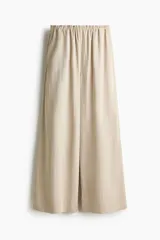 Pantalón de corte holgado en sarga suave color beige. Modelo con cintura elástica estándar, bolsillos en las costuras laterales y piernas rectas.