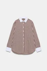 Camisa de manga larga con estampado de rayas verticales en tonos marrón y beige. Presenta cuello solapa y puños anchos en color blanco a contraste, con cierre frontal de botones.